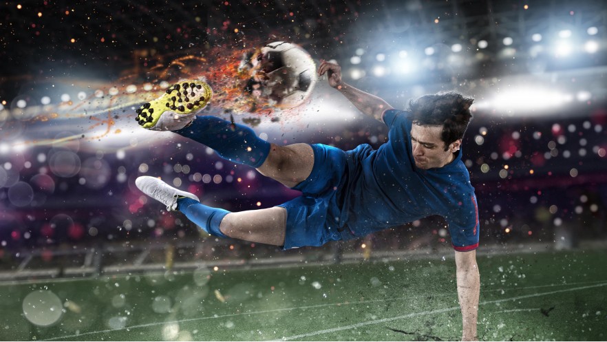 Image shows a soccer player jumping to kick the ball