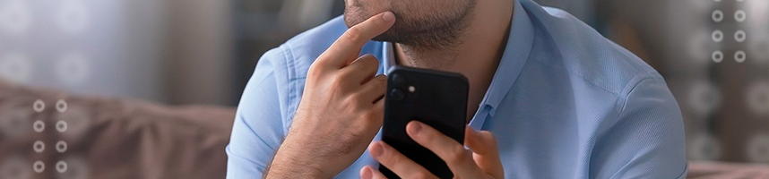 The image shows a man scratching his chin while holding a smartphone in his other hand.