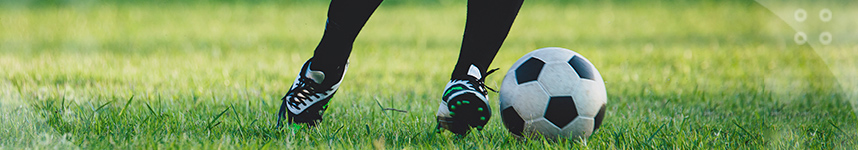 The image shows the feet of a soccer player kicking the ball.