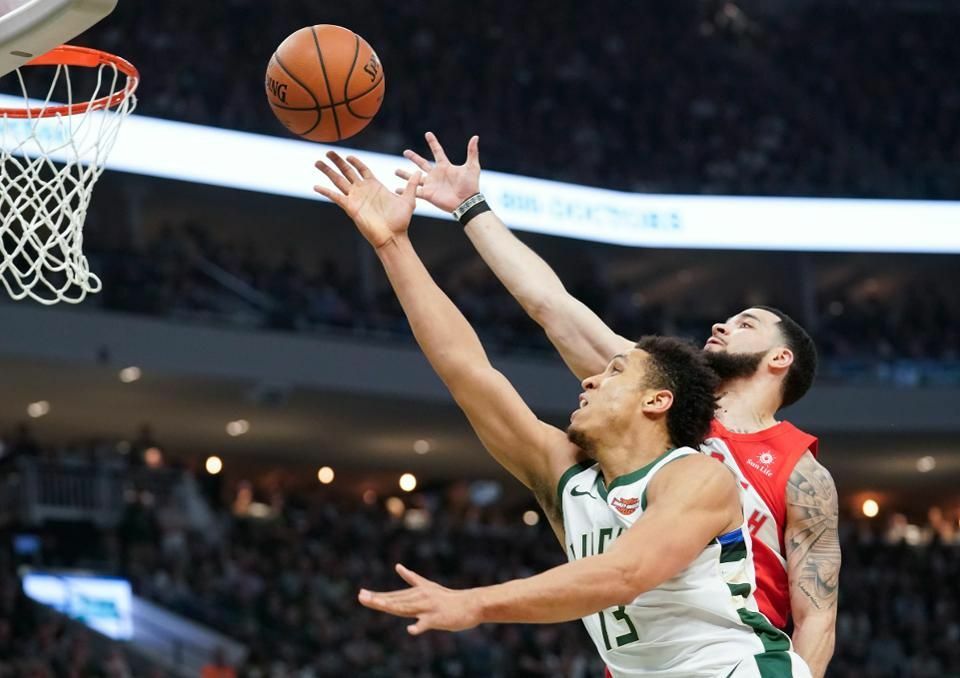 Fred VanVleet in the Raptors dark jersey soaring to the basket against the Bucks