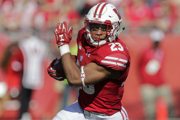 Jonathan Taylor carrying the ball in Wisconsin Badgers red jersey.