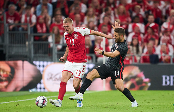 Rasmus Kristensen and Nikola Vlasic compete for a ball during a UEFA Nations League match.