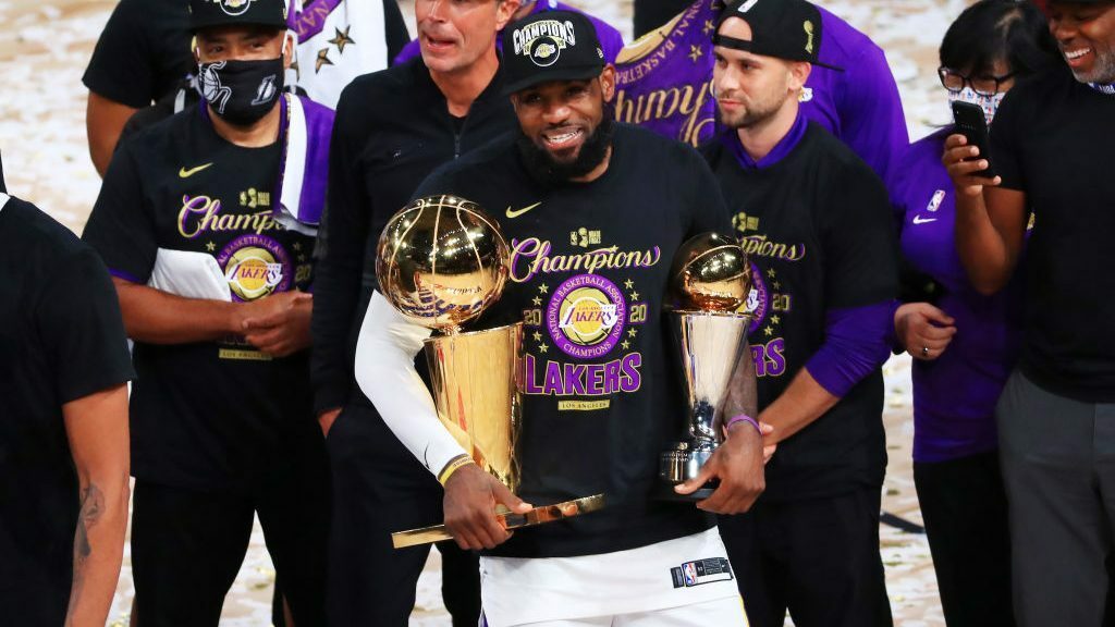 LeBron James, the GOAT, holding Finals MVP and Larry O'Brien trophies.